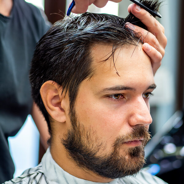 Un homme se fait couper les cheveux, illustrant des tendances capillaires pour 2026.