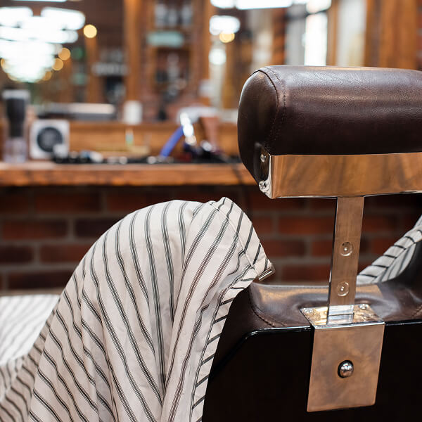 Une chaise de barbier avec une serviette posée dessus, prête pour un service de coiffure.